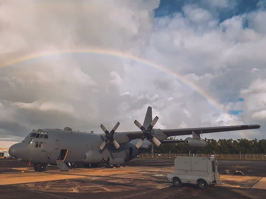 View of an EC-135 Compass Call from the side with a rainbow in the sky behind it.