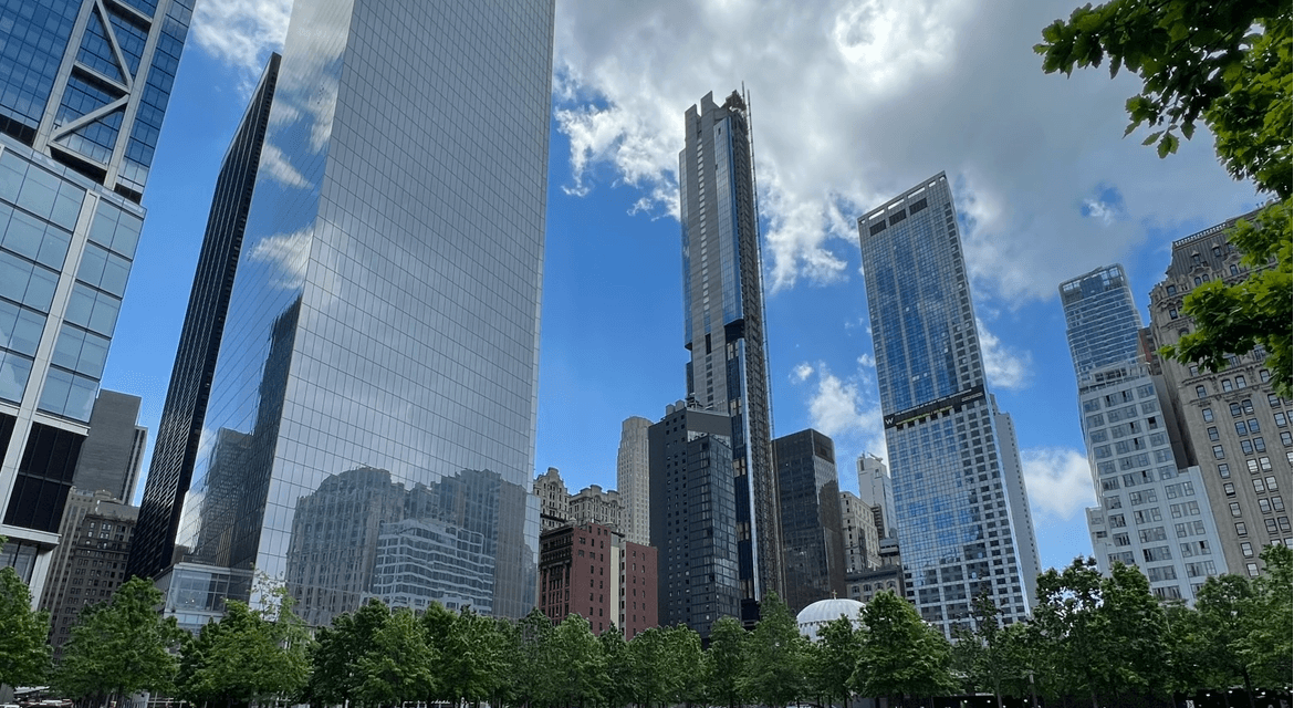 New York City skyline with blue skies and clouds behind it.